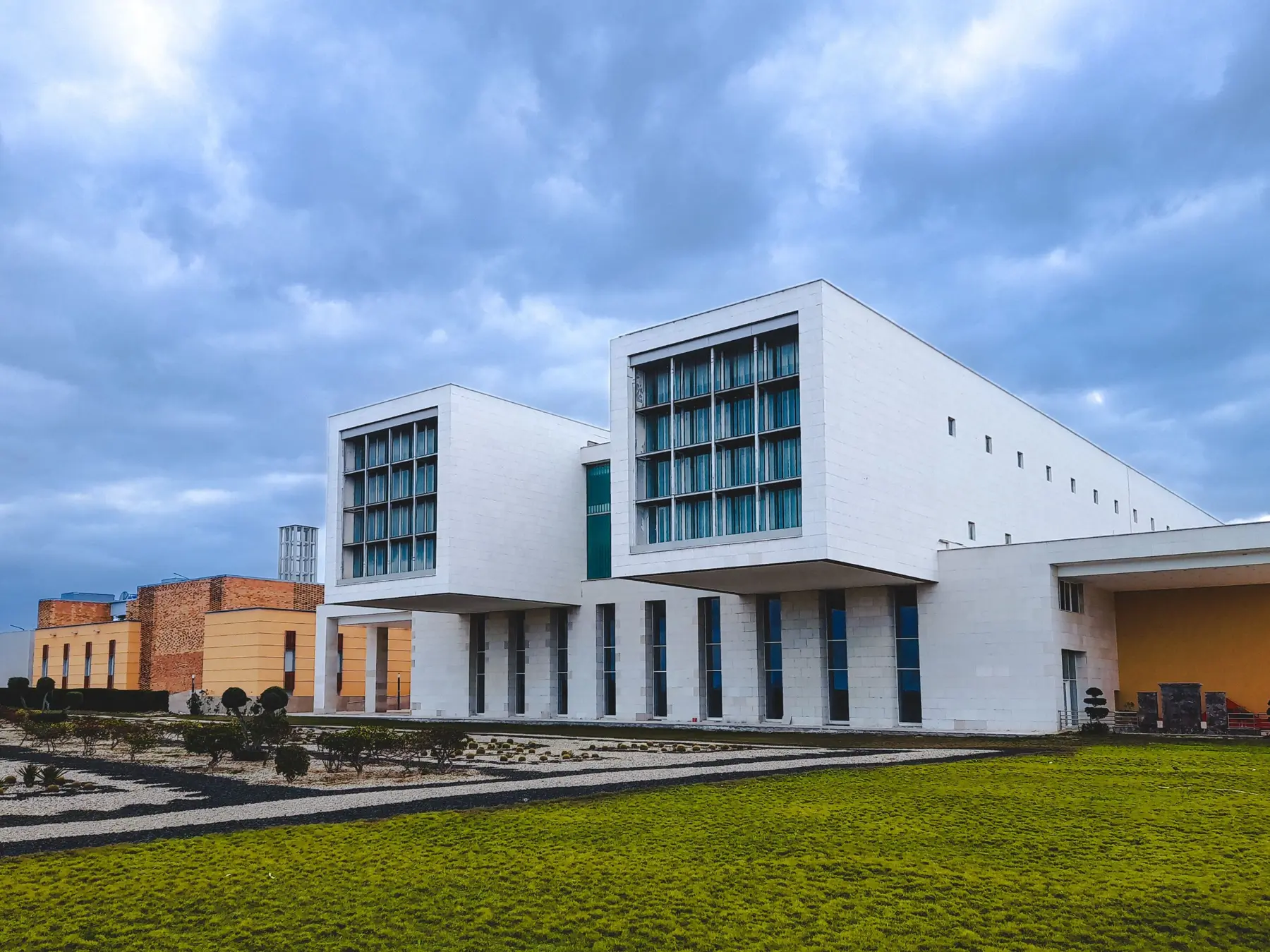 A modern white campus building under a cloudy sky